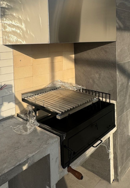 Materiales de parrillas estándar a medida
El material define no solo la estética, sino también el rendimiento y la durabilidad.
En nuestros proyectos trabajamos principalmente con dos configuraciones:
Parrillas completamente en acero inoxidable
Ofrecen mayor resistencia a la humedad, fácil mantenimiento y una estética más limpia. Funcionan muy bien en terrazas contemporáneas o espacios donde se busca uniformidad en los acabados.
Parrillas combinadas: acero inoxidable + fierro
Permiten un mejor comportamiento térmico. El acero inoxidable se utiliza en las partes visibles y expuestas, mientras que el fierro aporta mayor retención de calor en las zonas de trabajo.
Esta combinación resulta eficiente para un uso más intensivo de la parrilla.
La elección del material debe responder al uso real del espacio, no solo a la apariencia.